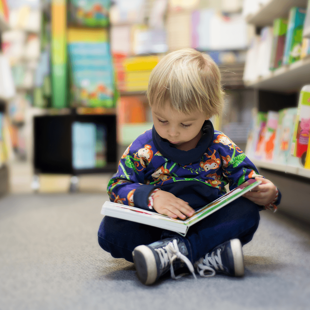 Pojke läser bok på golvet – lugna barnaktiviteter Göteborg på bibliotek