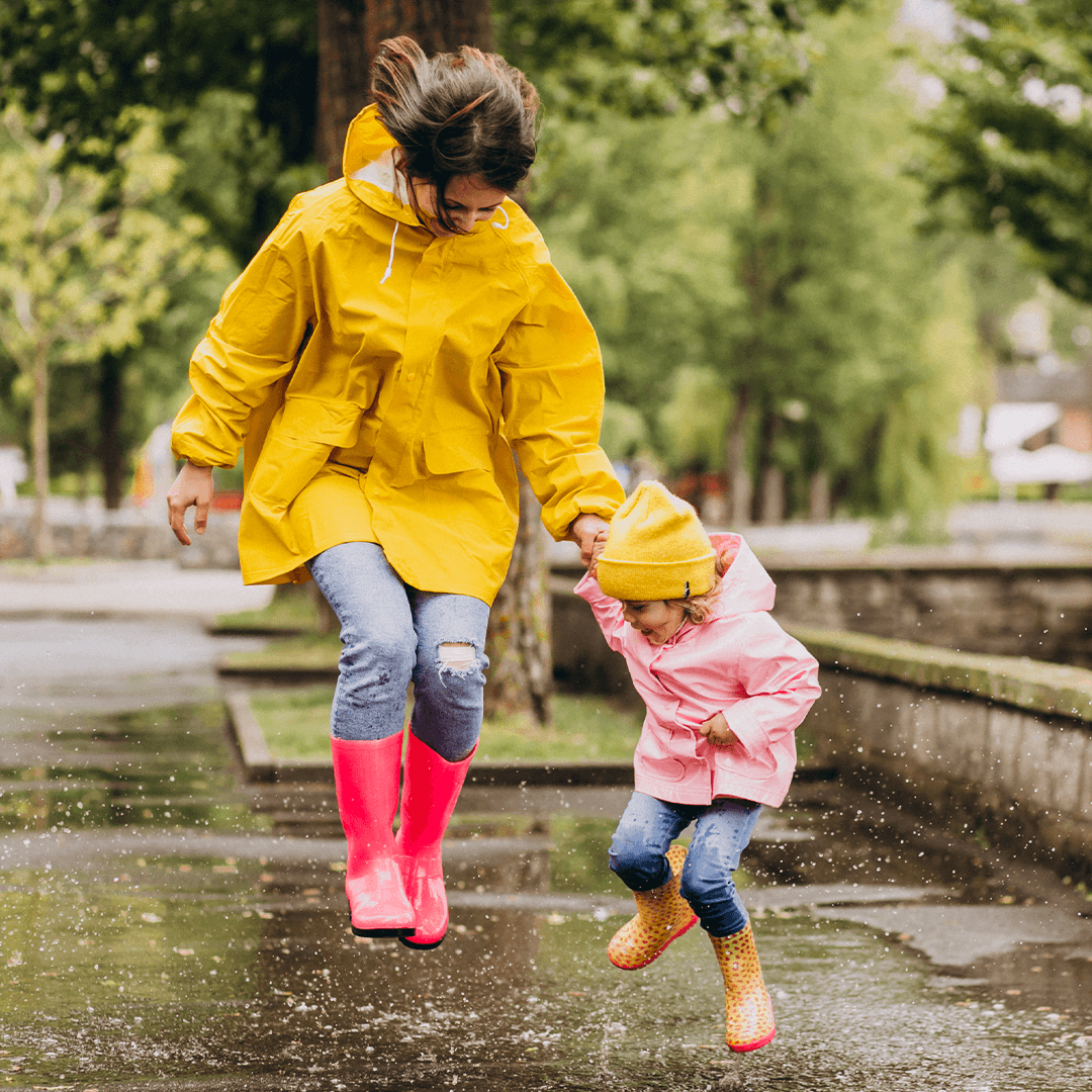 Mamma och dotter hoppar i vattenpölar – fartfylld lek i regnet.
