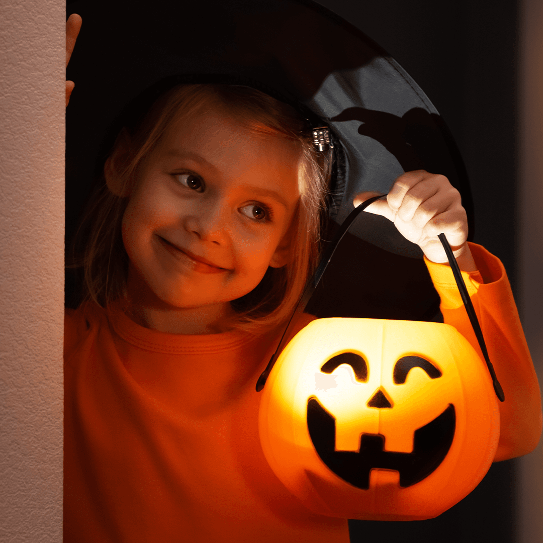 Girl holding a pumpkin lantern at Halloween