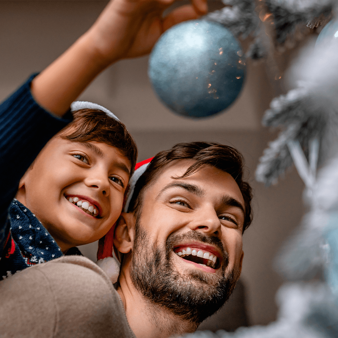 A father and son decorating the Christmas tree together.