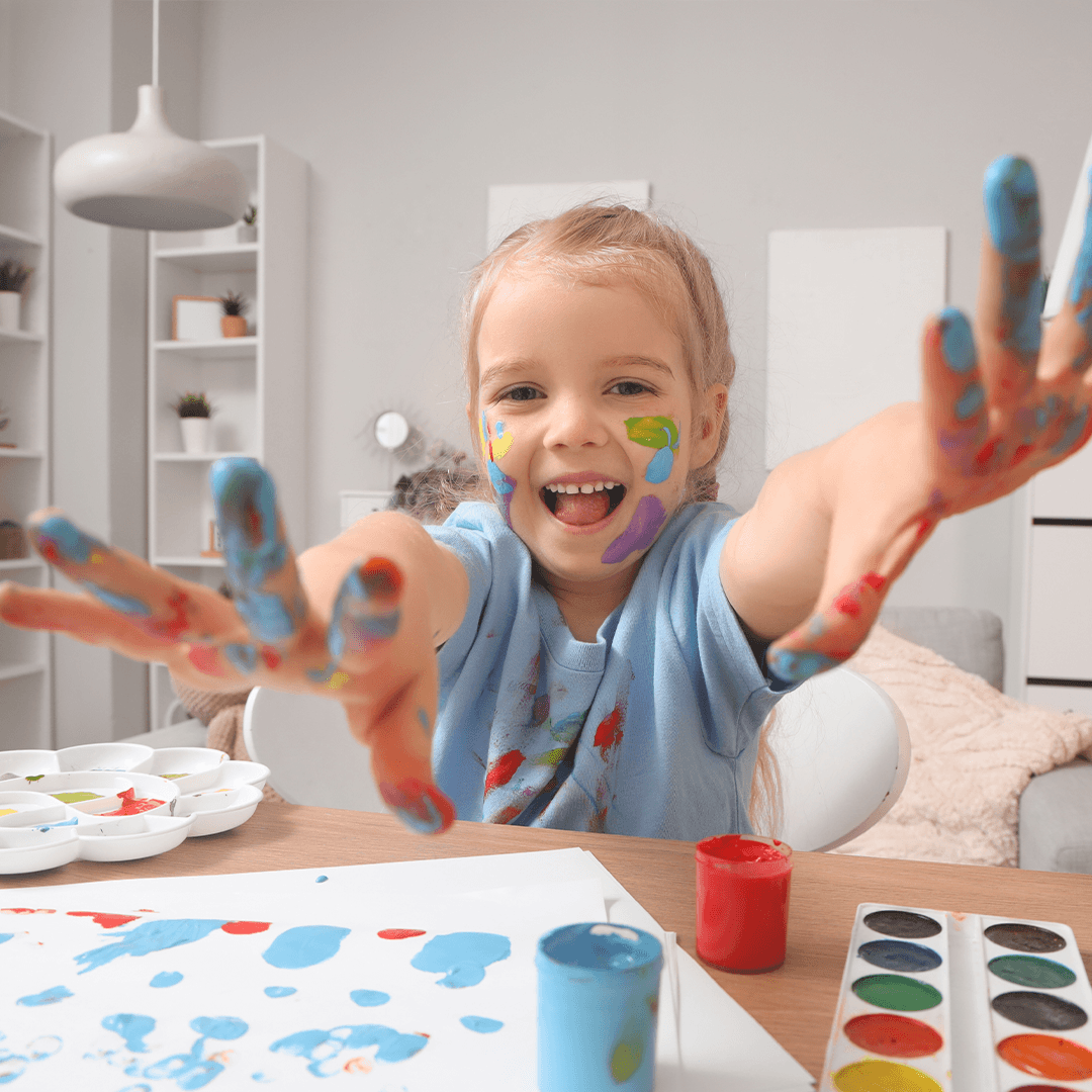 Child doing finger painting at home.