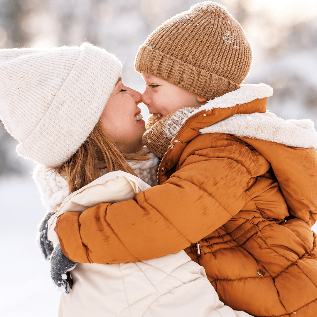 Mother and son hugging outdoors in winter weather.